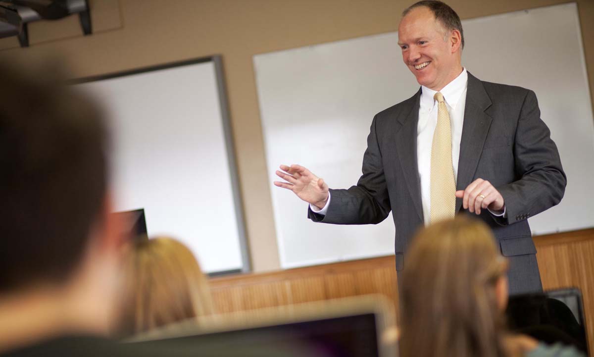 Photo of Professor David Raeker-Jordan in front of a white board lecturing to students.