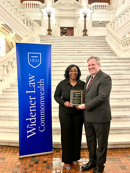 Arlene with Dean Hussey and a blue WLC sign receiving her award at the PA Capitol.