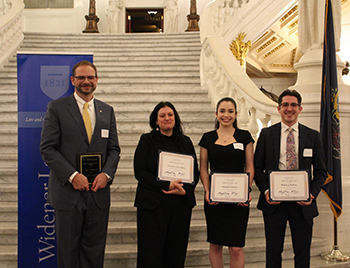 Image of award honorees standing in front of the marble Capitol stairs with a Widener Law Commonwealth banner. 