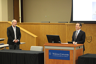 Doug Wolfberg '96 standing behind podium introducing keynote speaker Matt Savadsky