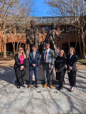 Image of Cassidy Hartle, Isaac Evans, Noah Chauvin, Margot Crouch and Paige Oustrich standing before a statue during a competition at William and Mary Law School/