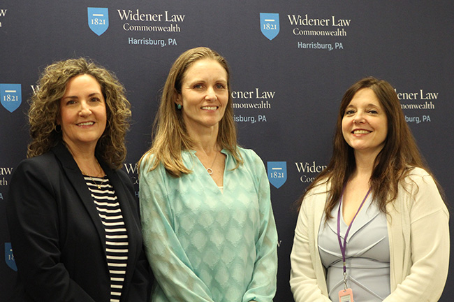 Mary Catherine Scott, Rebecca May-Cole, and Amy Whitworth stand together smiling in front of a Widener Law Commonwealth backdrop following the Reframing Aging event