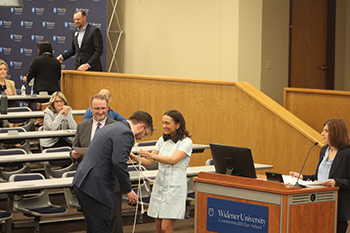 Image of Kiera Flannery draping cord over Max Oeler's neck during the student awards ceremony. 