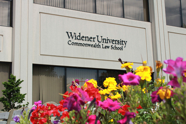 Image of Widener University Commonwealth Law School library building with an array of summer flowers in front of it in shades of purple, yellow and red hues.