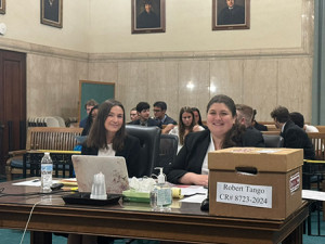 Rebecca Hitchiner from Widener University Delaware Law School and Jessica Poley from Widener University Commonwealth Law School seated behind a desk in a courtroom smiling at the camera. 