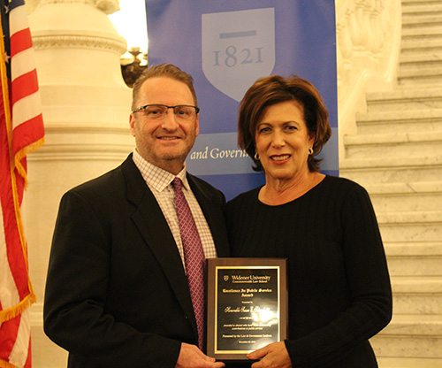 Judge Susan Schwab pictured with Dean cummings with an American flag in the background. 