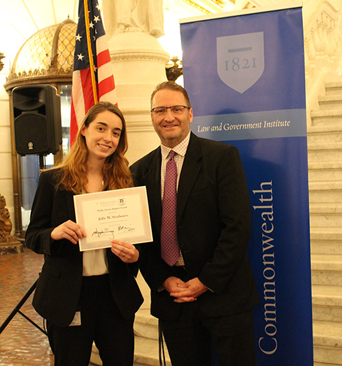 Julie Stenhouse pictured with Dean cummings with an American flag behind them. 