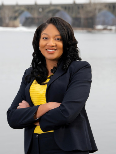 Image of Gabrielle Spisak, a woman wearing a yellow shirt and black blazer, smiling at the camera. 