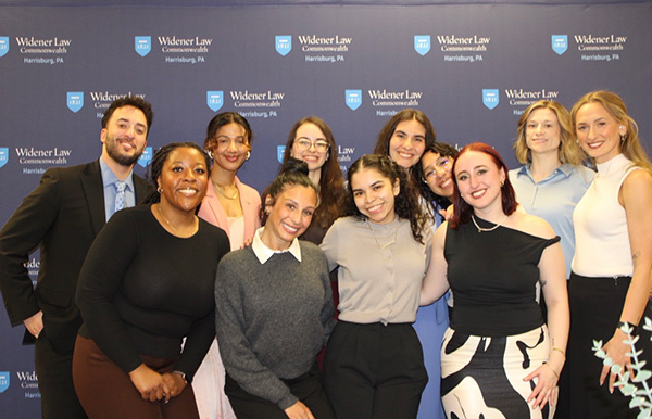 Image of the planning group standing in front of the Widener Law Commonwealth branded step and repeat. 