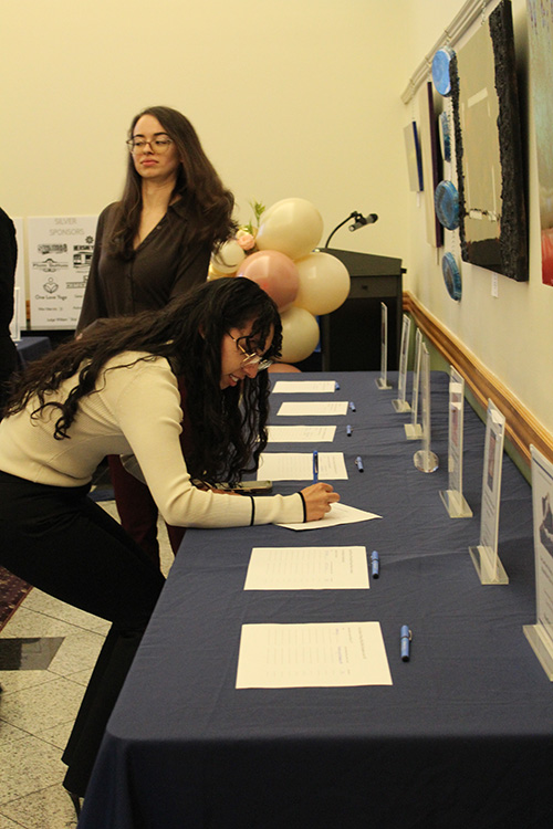 Image of student writing down bid during silent auction portion of the evening. 