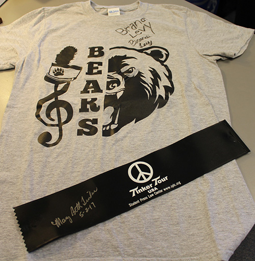 A signed gray T-shirt with a bear mascot and musical design, featuring the word "BEARS," alongside a black "Tinker Tour" armband with a peace symbol and handwritten signature.