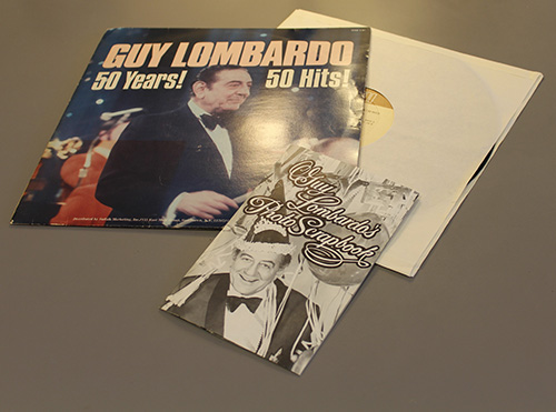 The image features a vinyl record set dedicated to Guy Lombardo. The record cover prominently displays a photograph of Guy Lombardo in a tuxedo, with the title "Guy Lombardo: 50 Years! 50 Hits!" in bold white and yellow lettering. 