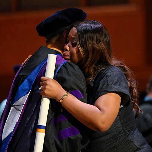 Image of Dean cummings embracing Toty Boley's fiancé on stage as she accepted his diploma posthumously. 