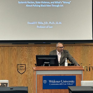 Professor Donald Tibbs standing in front of the podium delivering his remarks. 