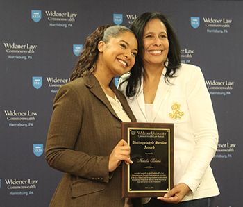Natalie Solano and her mother posting in front of the Widener Law Commonwealth branded step and repeat. Natalie is holding up her award. 