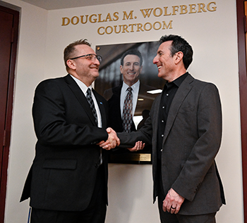 Dean andre douglas pond cummings shaking hands with Doug Wolfberg in front of his portrait. 