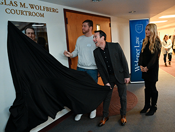 Douglas Wolfberg pulling the black drape off of his portrait outside the Wolfberg Courtroom. 