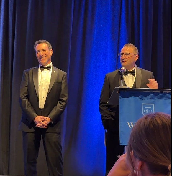 Dean cummings speaking at the podium alongside Doug Wolfberg.