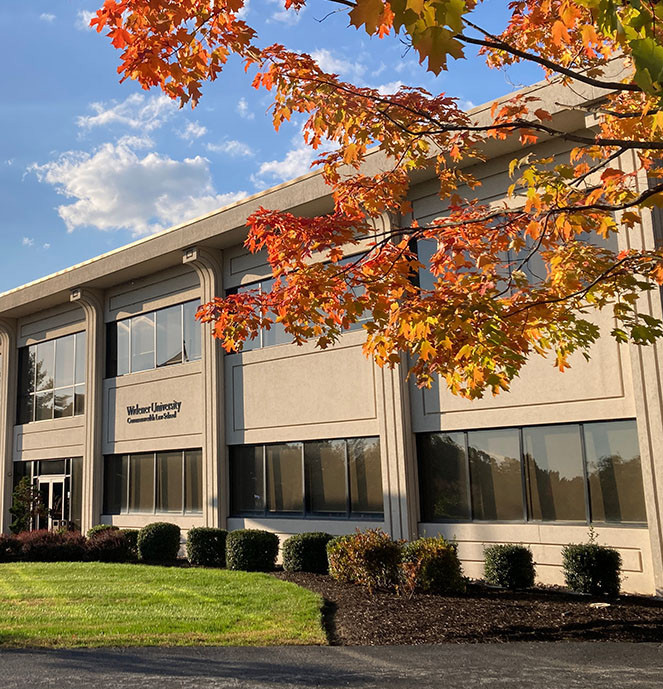 Front of library building showing WLC sign and fall-colored tree.