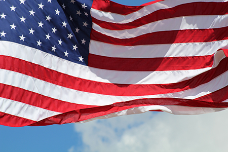 An image of the American flag waving in the wind against a clear blue sky