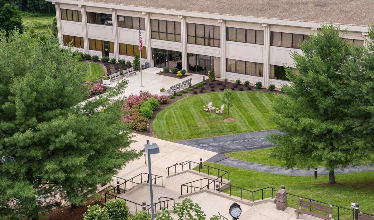 Aerial view of the Widener Law Commonwealth campus building, surrounded by manicured lawns, flowering shrubs, mature trees, and outdoor seating areas.