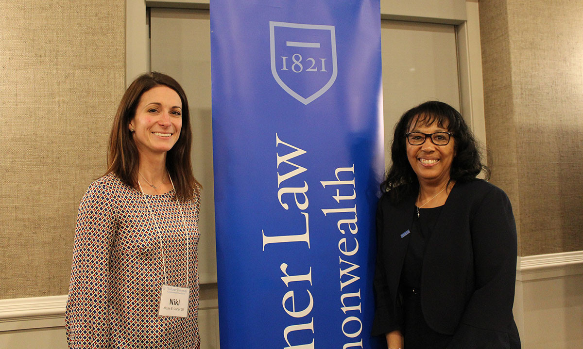 Nicole Carter and another attendee pose beside a Widener Law Commonwealth banner at the 2018 alumni awards ceremony.