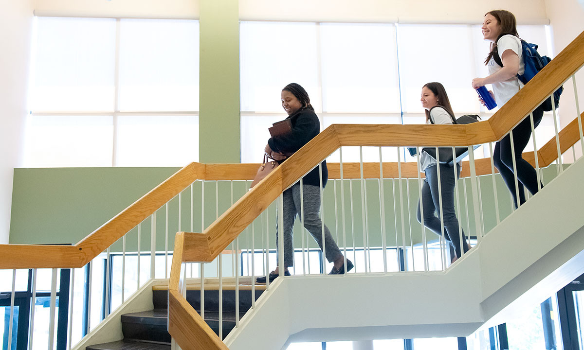 Three students walking down a stairwell.