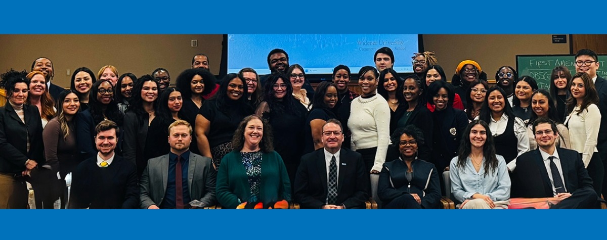 A large group of Widener Law Commonwealth Pathway Program participants, faculty, and staff pose together in a classroom, with a Widener University Commonwealth Law School presentation visible on the projector screen behind them.