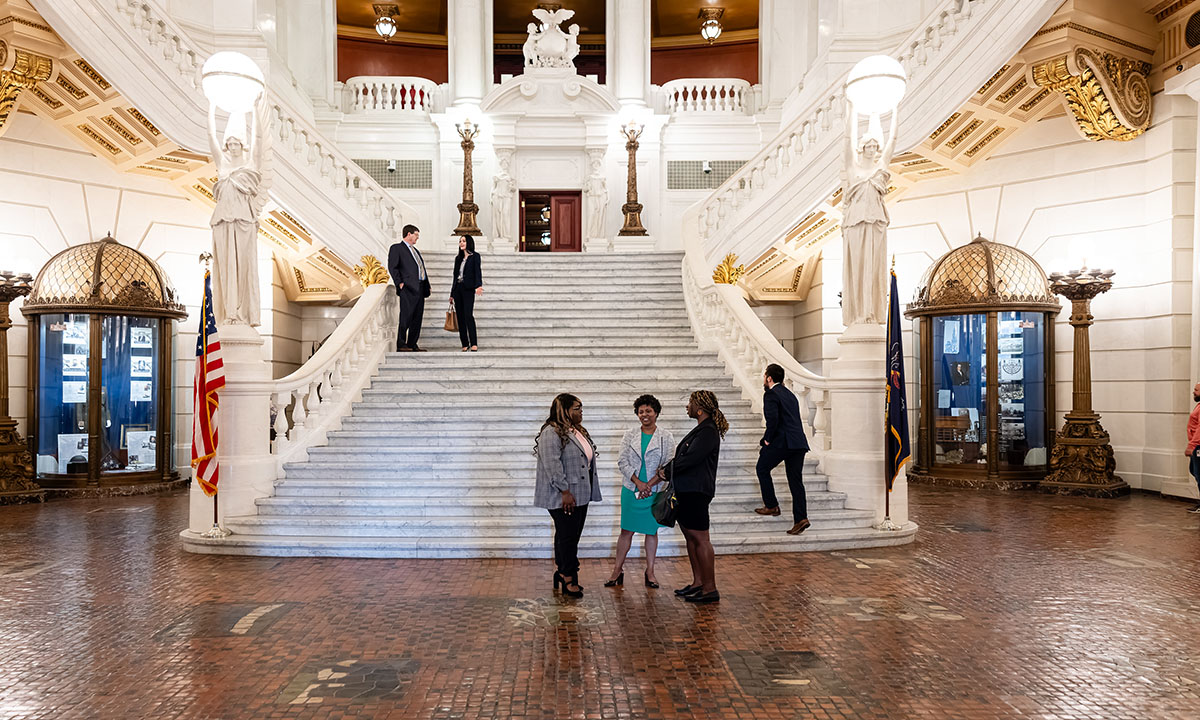 Students standing on the interior PA Capitol stairs talking to WLC faculty members.