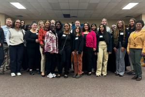 A large group of approximately twenty students and faculty poses together indoors at a Center for Equity and Justice Pathway Program gathering, filling the frame in a casual group arrangement.