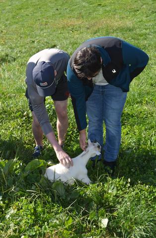Two students petting a baby goat. 