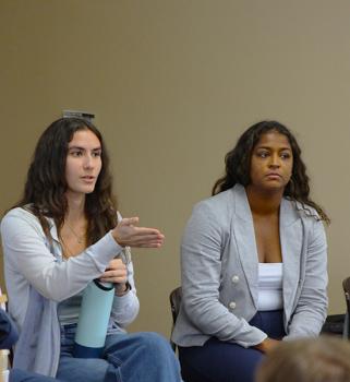Haley with one arm gesturing sitting next to Nia