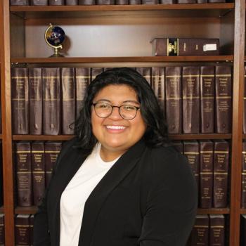 Headshot of student in front of legal books