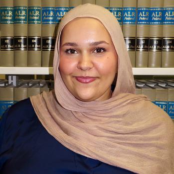 Headshot of student in front of legal books
