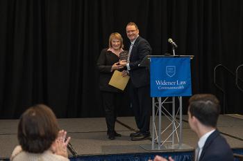 Dean andre douglas pond cummings posing on stage with Ann Marie Yastishock receiving her award. 
