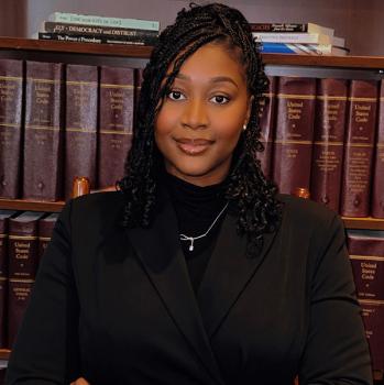 Headshot of student in front of legal books