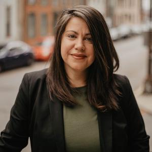 WLC alumna standing on a city street with a suit jacket in a headshot pose