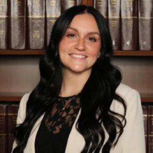 Headshot of student in front of legal books